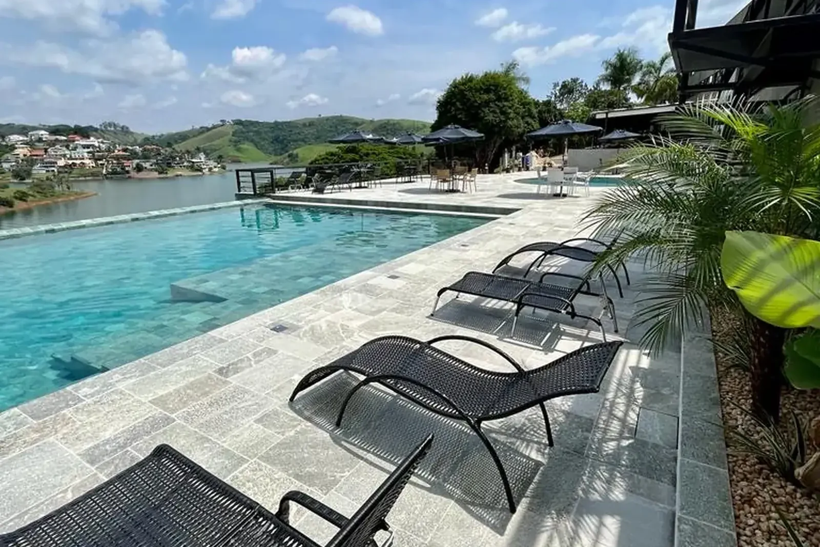 Piscina com espreguiçadeiras e vista para a represa